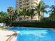 Outdoor pool with a view of a condominium building surrounded by lush palm trees at 435 S Gulfstream Ave # 601, Sarasota, FL 34236