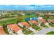 Aerial view of a home with a tile roof, nicely landscaped yard, and a pond on a golf course in the background at 4909 Clubview E Ct, Bradenton, FL 34203