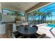 Outdoor kitchen featuring built-in grill, stainless steel fridge, and dining table with view of the pool and scenery at 5602 Tidewater Preserve Blvd, Bradenton, FL 34208