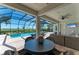 Covered patio with lounge area and table overlooking the sparkling pool and relaxing scenery at 5602 Tidewater Preserve Blvd, Bradenton, FL 34208
