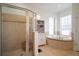 Luxurious bathroom featuring a glass-enclosed shower, soaking tub, and a well-organized linen cabinet at 5715 Sea Trout Pl, Apollo Beach, FL 33572