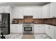 Kitchen with white cabinets, stainless steel appliances, and a tiled backsplash that adds warmth to the space at 5715 Sea Trout Pl, Apollo Beach, FL 33572