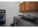 Well-equipped laundry room with modern, front loading washer and dryer, and wooden cabinets at 5715 Sea Trout Pl, Apollo Beach, FL 33572