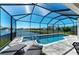 Screened-in pool and spa offers an amazing lake view beyond a black fence and lawn at 5822 Title Row Dr, Bradenton, FL 34210