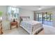 This bedroom features a patterned quilt, wood-look nightstand, and sliding glass doors to a sunroom at 622 Spring Lakes Blvd, Bradenton, FL 34210