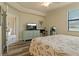 Cozy bedroom with a dresser, TV, stylish mirror, and wood-look flooring, illuminated by natural light at 6519 Grand Estuary Trl # 101, Bradenton, FL 34212