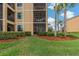Exterior view of a condo featuring a screened balcony, complemented by lush landscaping and fresh green grass at 6519 Grand Estuary Trl # 101, Bradenton, FL 34212
