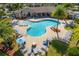 Aerial view of a resort-style pool area surrounded by lush greenery, lounge chairs and a cozy fire pit at 6519 Grand Estuary Trl # 101, Bradenton, FL 34212