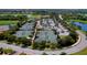 Aerial view of multiple tennis courts surrounded by lush landscaping, a pool, and nearby parking at 6519 Grand Estuary Trl # 101, Bradenton, FL 34212