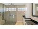 Bright bathroom with a seamless glass shower, rain shower head, a built-in bench, and granite countertops at 6621 The Masters Ave, Lakewood Ranch, FL 34202