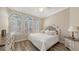 This bedroom features arched windows with shutters, wood-look floors, and a white upholstered headboard at 6621 The Masters Ave, Lakewood Ranch, FL 34202