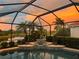 Stunning screened pool with a tranquil lake view and vibrant sunset backdrop, perfect for relaxing and entertaining at 6621 The Masters Ave, Lakewood Ranch, FL 34202