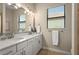 Well-lit bathroom showcasing a double vanity with white cabinetry, a mirror, and a window at 7036 Whittlebury Trl, Lakewood Ranch, FL 34202
