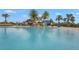 Resort-style community pool with beach entry, splash pad, and clubhouse under a bright blue sky at 7036 Whittlebury Trl, Lakewood Ranch, FL 34202