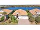 Waterfront home featuring a tile roof, brick driveway, a well-manicured yard, and an attached two car garage at 7036 Whittlebury Trl, Lakewood Ranch, FL 34202