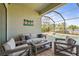 Screened patio offers comfortable seating, a coffee table, and scenic views of the pool and lake at 7036 Whittlebury Trl, Lakewood Ranch, FL 34202