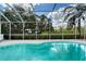 Enclosed pool surrounded by landscaping and green pastures creating a calm backyard oasis at 7108 229Th E St, Bradenton, FL 34211