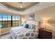 Well-lit bedroom with tray ceiling, large window, and patterned bedding at 7612 Lake Vista Ct # 406, Lakewood Ranch, FL 34202