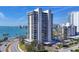 View of a modern, white high-rise apartment building with waterfront views in a tropical setting with palm trees at 770 S Palm Ave # 203, Sarasota, FL 34236