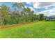 Landscaped backyard featuring green grass, mulch beds, and a wooded backdrop at 8124 115Th E Ave, Parrish, FL 34219