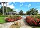 Inviting pool entrance framed by vibrant red flowers and lush tropical landscaping at 8951 Veranda Way # 621, Sarasota, FL 34238