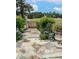 Scenic stone pathway leading to an iron gate, surrounded by lush greenery and colorful flowers at 10157 Sunburst Ct, Spring Hill, FL 34608