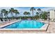 The inviting community pool is surrounded by palm trees and lounge chairs at 111 Whispering Sands Cir # V38, Sarasota, FL 34242