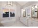 Spa-like bathroom with a soaking tub, double vanity, and elegant chandelier lighting at 112 50Th St, Holmes Beach, FL 34217