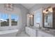 Spa-like bathroom featuring dual vanities, a soaking tub, and elegant lighting at 112 50Th St, Holmes Beach, FL 34217