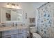 Well-lit bathroom features a vanity with granite countertops, a toilet, and a seashell-themed shower curtain at 112 50Th St, Holmes Beach, FL 34217