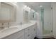 Bright bathroom featuring double sinks, decorative mirrors and a glass enclosed walk-in shower with pebble floor at 112 50Th St, Holmes Beach, FL 34217