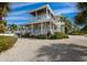 Stunning two-story coastal home featuring wrap-around porch and professionally landscaped yard with tropical foliage at 112 50Th St, Holmes Beach, FL 34217