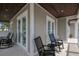 Inviting covered porch features rocking chairs and stylish exterior finishes and ample natural light at 112 50Th St, Holmes Beach, FL 34217