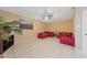 Bright living room with tile floors, ceiling fan, large plant, red sofas, and tan walls at 1224 Inverness St, Port Charlotte, FL 33952
