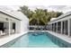Beautiful in-ground swimming pool surrounded by a pristine white patio, palm trees, and lush tropical foliage at 1354 Westway Dr, Sarasota, FL 34236