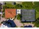 Aerial view of a tennis court and a house with a clay roof surrounded by lush greenery and manicured lawns at 1485 Gulf Of Mexico Dr # 205, Longboat Key, FL 34228