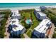 Beautiful aerial view highlights white condos, a sparkling pool, and a direct path to the sandy beach at 1485 Gulf Of Mexico Dr # 205, Longboat Key, FL 34228
