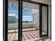 View from balcony shows beachfront property through an open sliding glass door with red tiled patio and white pergola at 1485 Gulf Of Mexico Dr # 205, Longboat Key, FL 34228
