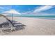 Beach scene with several lounge chairs and umbrellas with blue sky at 1485 Gulf Of Mexico Dr # 205, Longboat Key, FL 34228