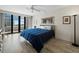 Bedroom with a large window, hardwood floors, modern lamp, and dark blue bed, filled with natural light at 1485 Gulf Of Mexico Dr # 205, Longboat Key, FL 34228