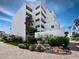 Bright white condominium building with lush landscaping under a blue sky at 1485 Gulf Of Mexico Dr # 205, Longboat Key, FL 34228