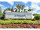 Avelina Wellen Park community entrance featuring a decorative sign, lush landscaping, and beautiful flower beds at 18736 Toulon Ct, Venice, FL 34293