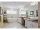 Bright bathroom featuring dual sinks, granite counters, soaking tub, and a walk-in shower at 201 Eaglenook Way, Osprey, FL 34229
