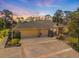 Home with a spacious three-car garage, mature trees, and expansive driveway under a beautiful sunset sky at 201 Eaglenook Way, Osprey, FL 34229