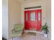 Cozy front porch with a red door, tiled floor, and decorative chair at 201 Eaglenook Way, Osprey, FL 34229