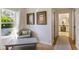 Hallway with a table, chair and framed artwork on the walls leading to a naturally lit bathroom at 201 Eaglenook Way, Osprey, FL 34229