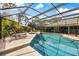 A sparkling screened-in pool with hot tub and seating areas surrounded by lush landscaping at 201 Eaglenook Way, Osprey, FL 34229