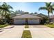 Villa-style home with a well-manicured lawn, palm trees, and a brick driveway, offering a serene setting at 2123 Lynx Run, North Port, FL 34288
