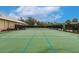 Well-maintained tennis court with clear lines, surrounded by mature trees and a privacy fence at 2123 Lynx Run, North Port, FL 34288