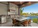 Outdoor kitchen with stainless steel appliances, seating, and waterfront views at 242 Oak Ave, Anna Maria, FL 34216